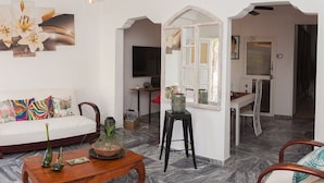 A living room with a sofa, a coffee table, and a TV. There is a mirror on the wall and a door leading to another room. - Casa La Reforma TRINIDAD (Trinidad)
