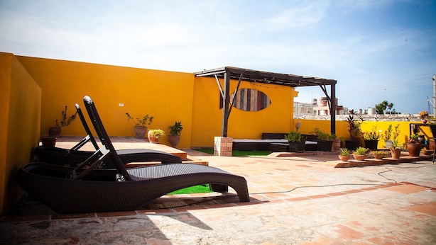 A patio with wicker lounge chairs, potted plants, and a pergola structure. - Casa La Reforma TRINIDAD (Trinidad)