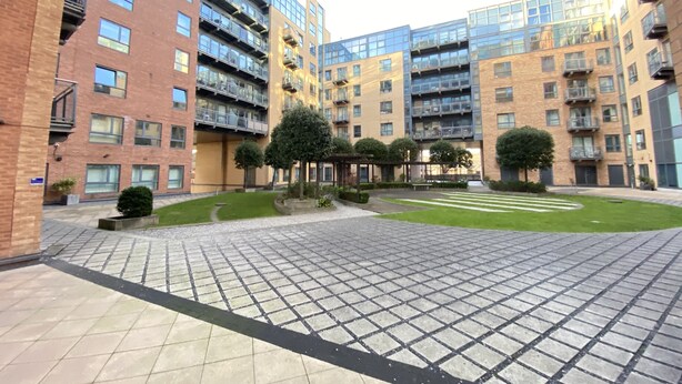 Un patio con edificios de apartamentos modernos, un sendero pavimentado y abundante vegetación.