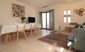 A spacious living area with a dining table, chairs, a sofa, and a TV.
