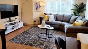 A living room with a sofa, TV, coffee table, and decorative items. - 10 minute Walk GA Aquarium and other Major Attractions (Atlanta)