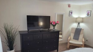 A bedroom with a bed, a dresser, a TV, a chair, and a lamp. - 10 minute Walk GA Aquarium and other Major Attractions (Atlanta)