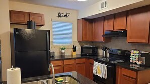 A modern kitchen with wooden cabinets, a black refrigerator, a microwave, and a stove. - 10 minute Walk GA Aquarium and other Major Attractions (Atlanta)