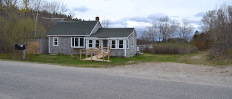 A two-story house with a porch, a small attached garage, and a wooden staircase leading to the front door.