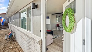 A modern house with a covered porch, a brick wall, and a green wreath on the door. - Relaxing Hot Tub and Fire Pit! Great for Families or Business - Perfect Location (Loveland)