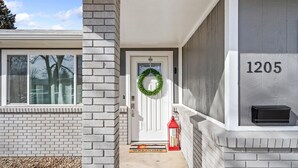 A house with a white door, a number '1205' on the wall, a mailbox, and a red lantern on the porch. - Relaxing Hot Tub and Fire Pit! Great for Families or Business - Perfect Location (Loveland)