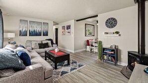 A modern living room with a sofa, coffee table, and a fireplace. - Relaxing Hot Tub and Fire Pit! Great for Families or Business - Perfect Location (Loveland)
