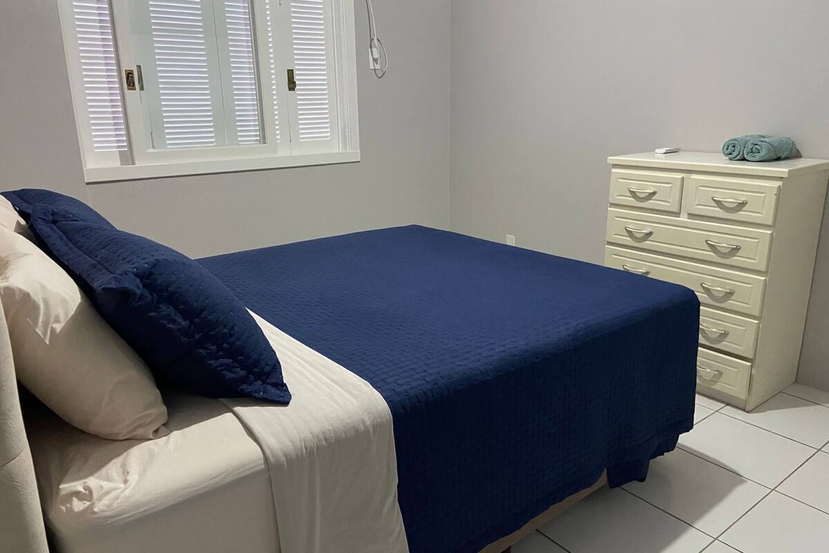 Un dormitorio con cama, cómoda y ventana con persianas.
