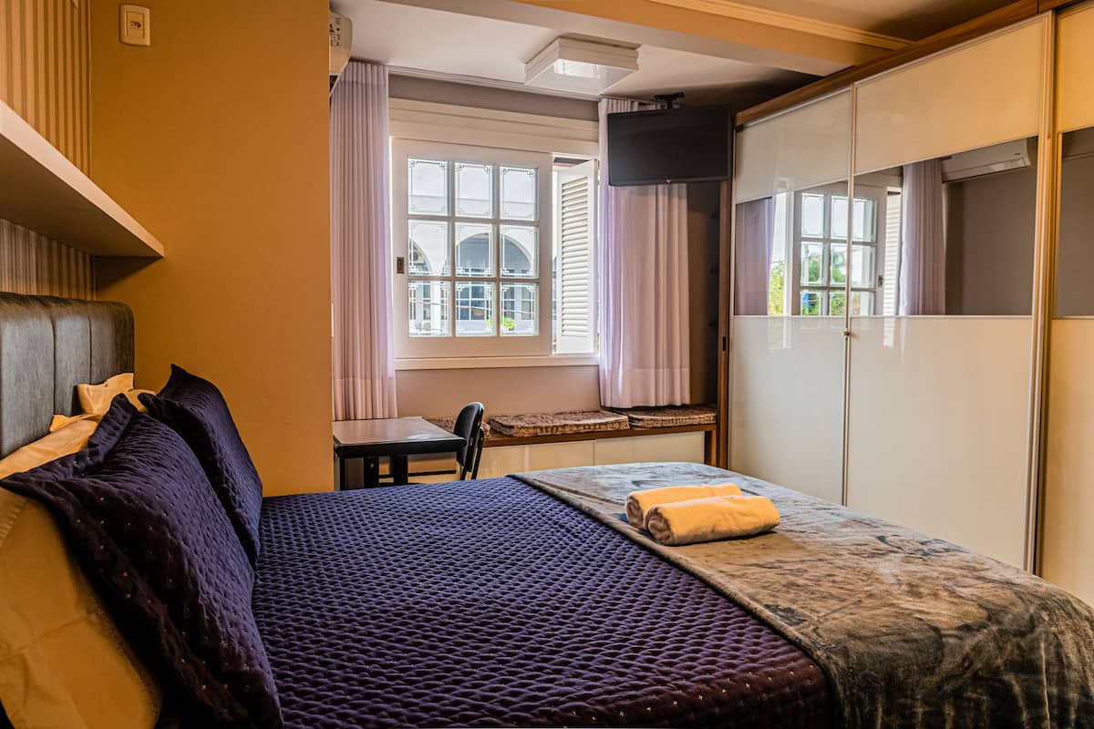 Un dormitorio con cama, escritorio y armario.