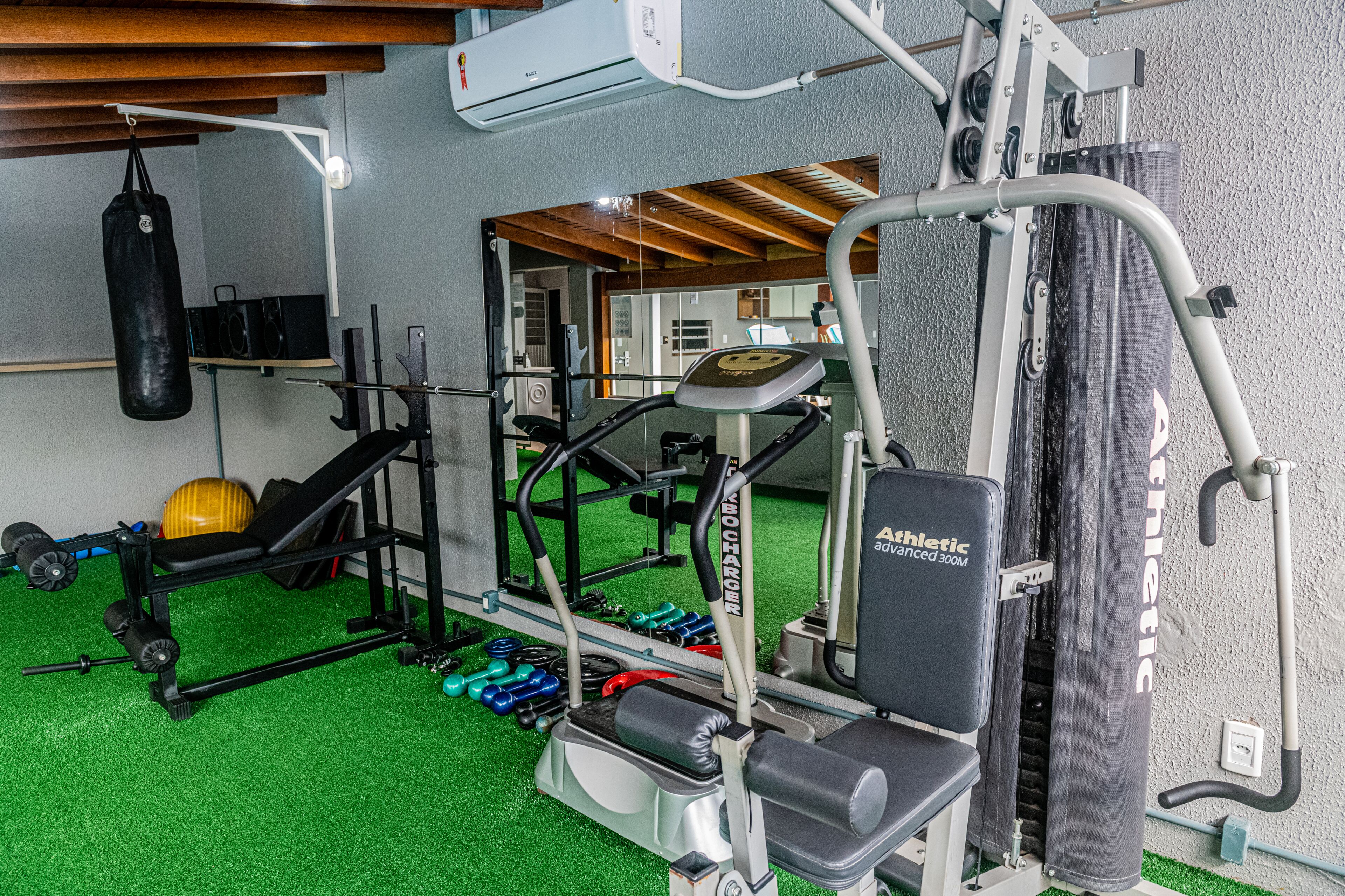 Un gimnasio con equipos de ejercicio variados, como cintas de correr, bancos de pesas y mancuernas.