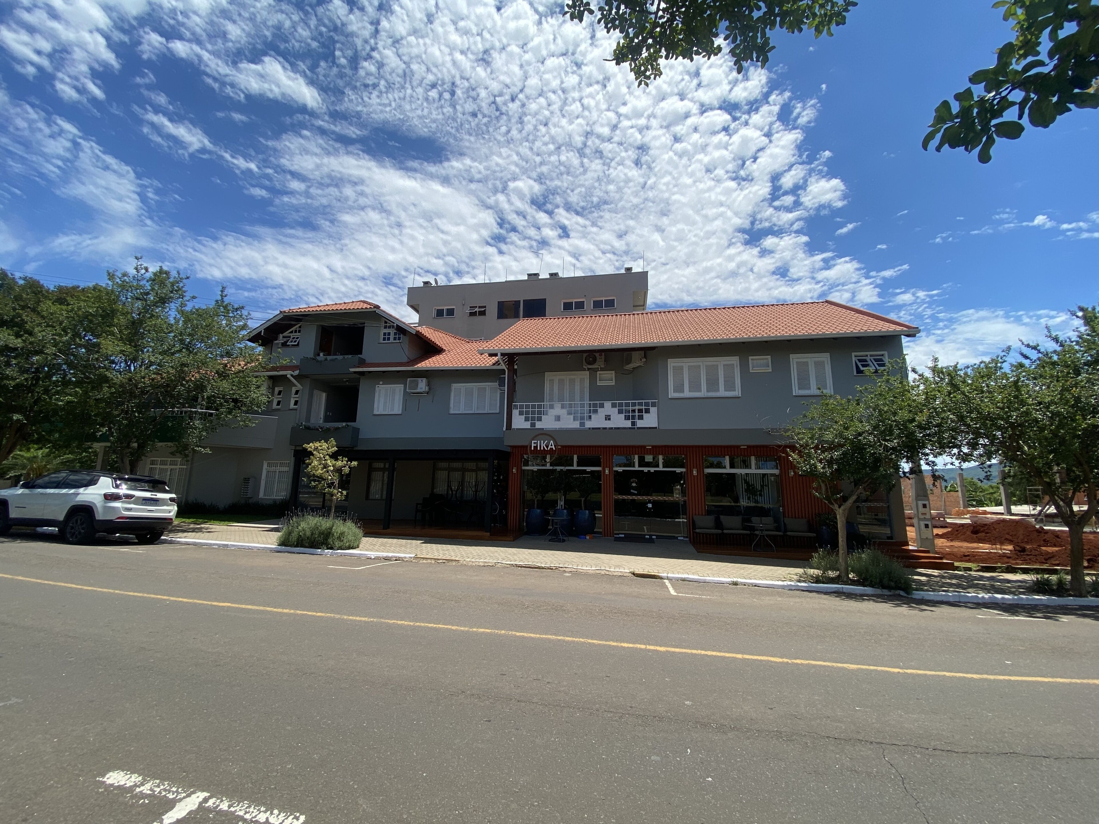 A two-story building with a storefront labeled "FIKA" and a parking lot in front.