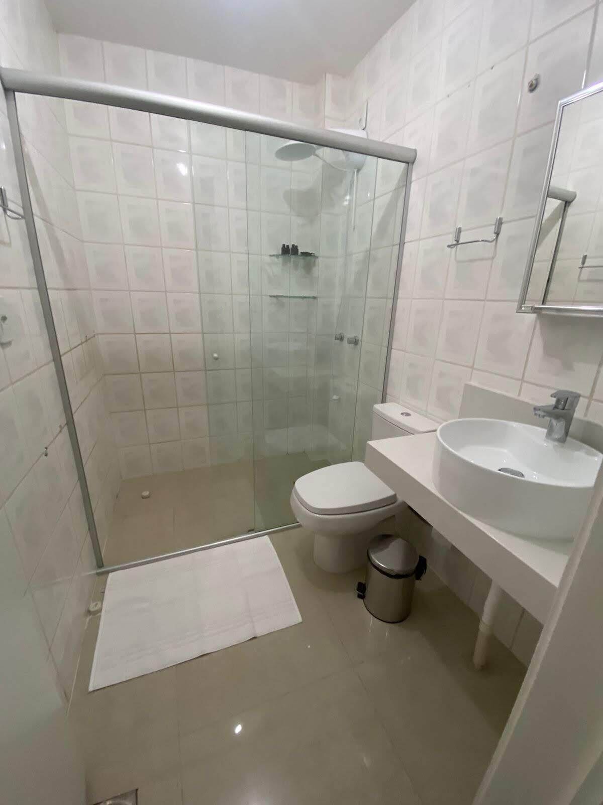 Uma casa de banho moderna com cabine de duche em vidro, sanita e lavatório.