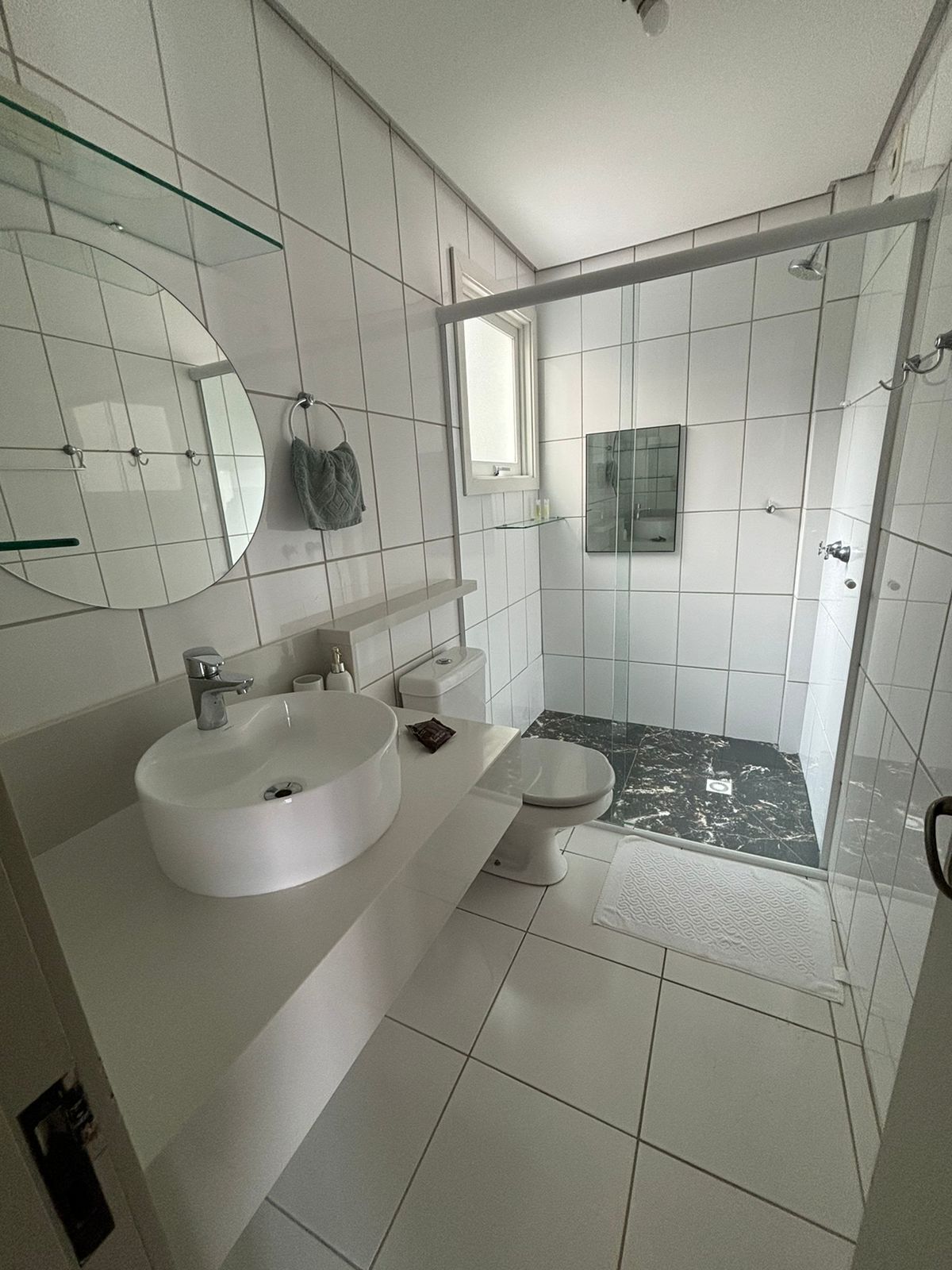 A modern bathroom with a large white sink, a toilet, and a shower area.