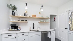Een moderne keuken met witte kasten, roestvrijstalen apparatuur en houten planken.
