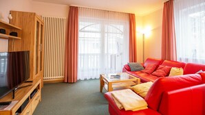 Ein modernes Wohnzimmer mit einem roten Ledersofa, einer Holz-Unterhaltungseinheit mit Fernseher und einem Glastisch.