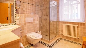 Ein Badezimmer mit Dusche, Toilette, Waschbecken und einem Fenster mit Vorhängen.