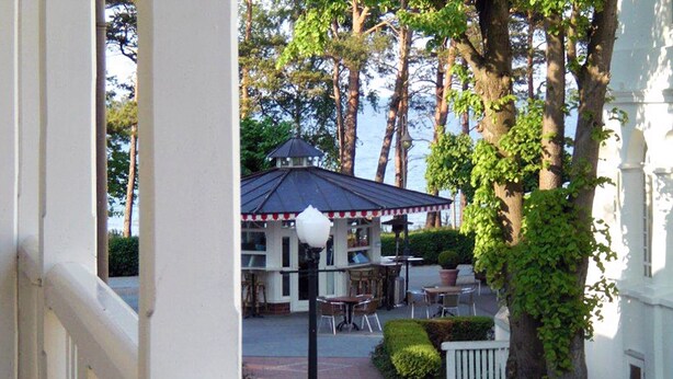 Ein Terrassenbereich mit Sitzgelegenheiten im Freien, einer Überdachung und einem Weg zu einem Gebäude.