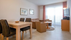 Un salon moderne avec une table à manger, des canapés et un téléviseur.