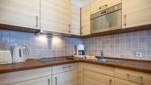 Une cuisine moderne avec des meubles en bois, une cuisinière en acier inoxydable, une machine à café et un évier.