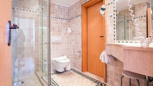 Un bagno con box doccia in vetro, un water e un lavabo con specchio.