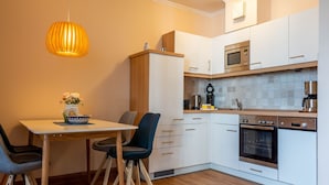 Eine moderne Küche mit weißen Schränken, einem Holztisch und einer hängenden Pendelleuchte.