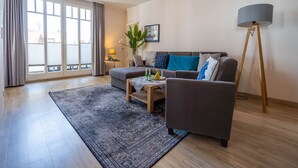 Un salon moderne comprenant un canapé, un fauteuil, une table basse et un lampadaire.
