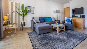 Un salon moderne avec un canapé gris, une table basse, un lampadaire et un téléviseur.