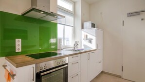 Eine moderne Küche mit weißen Schränken, einer grünen Spritzschutzwand, einem eingebauten Backofen, einer Mikrowelle und einem Fenster für natürliches Licht.
