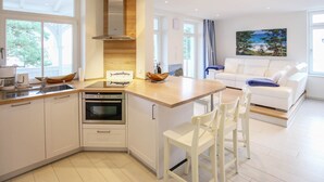 A modern kitchen with white cabinetry, a built-in oven, and a large window. - Apartment with sea view, 2 bedrooms and balcony (Ostseebad Binz)