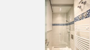 A modern bathroom with a glass shower enclosure, a white toilet, and a towel rack. - Apartment with sea view, 2 bedrooms and balcony (Ostseebad Binz)