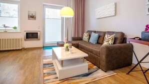 A modern living room with a brown sofa, a white coffee table, and a colorful rug. - Apartment with sea view, 1 bedroom and balcony (Ostseebad Binz)