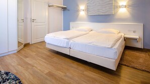 A double bed with white bedding, a bedside table, a wall-mounted light, and a mirror. - Apartment with sea view, 1 bedroom and balcony (Ostseebad Binz)