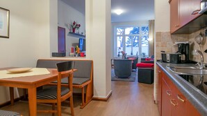 A modern kitchen with wooden cabinets, a stainless steel sink, and a dining area with a wooden table and striped chairs. - Apartment with sea view and 2 bedrooms (Ostseebad Binz)