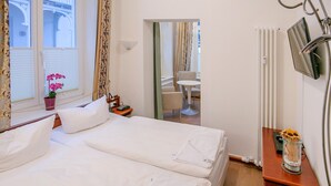 A hotel room with a bed, a bedside table, a TV, and a window with curtains. - Apartment with sea view and 2 bedrooms (Ostseebad Binz)