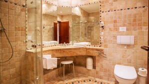 A bathroom with a glass-enclosed shower, a sink with a mirror, a toilet, and a small stool. - Apartment with sea view and 2 bedrooms (Ostseebad Binz)