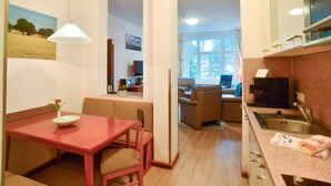 Un espace de vie compact comprenant un coin repas, une cuisine et un coin salon offrant une vue sur l’extérieur.