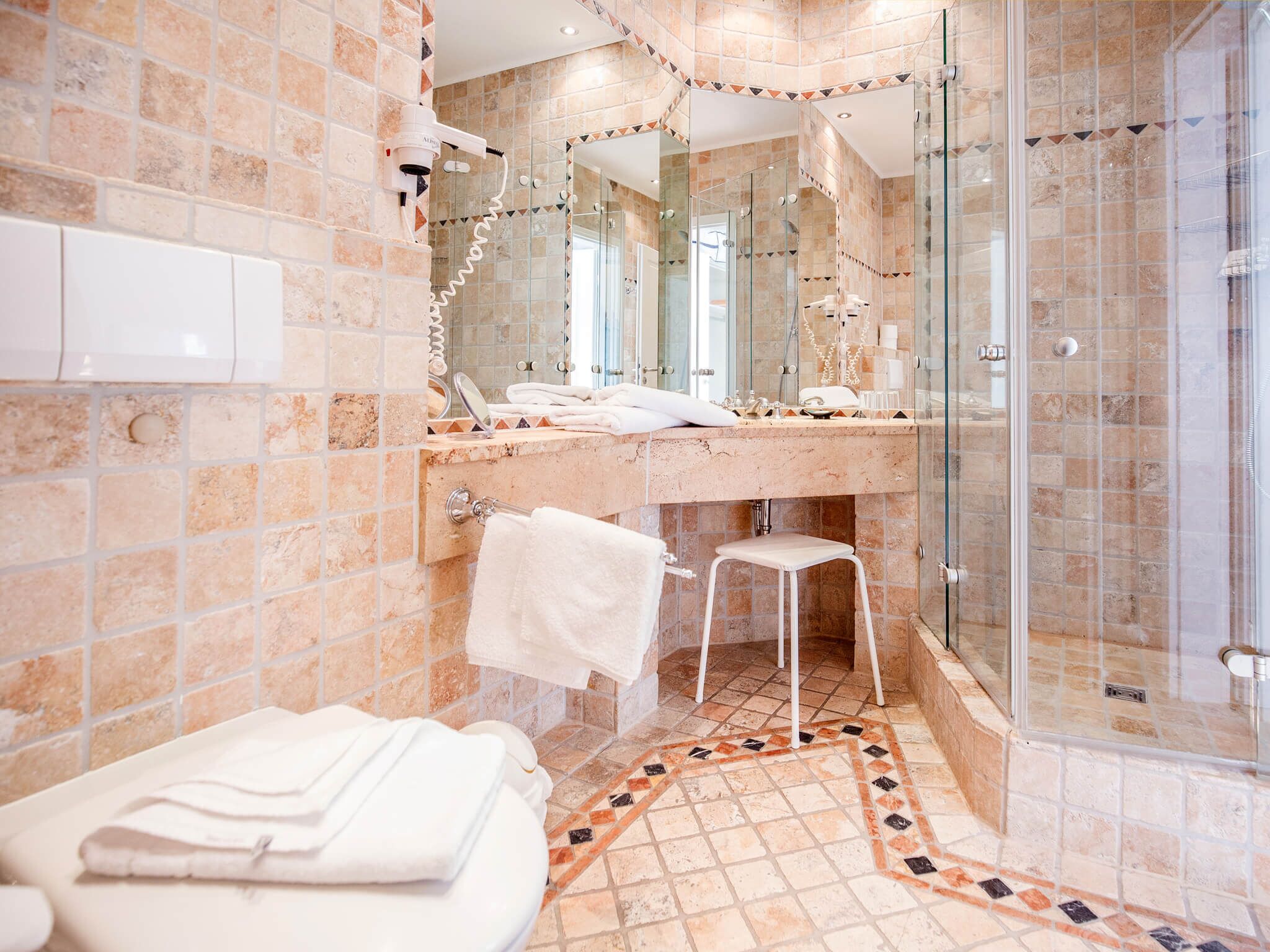 Un baño con cabina de ducha de vidrio, tocador con espejo y retrete.