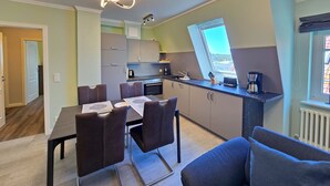 Et moderne køkken med spiseplads, med et spisebord med stole, en indbygget ovn og et vindue med udsigt.