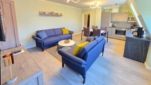 En moderne stue med sofa, sofabord og et spiseområde med stole.