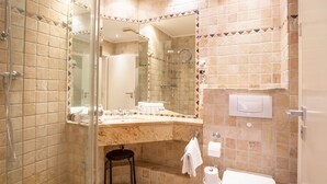 Ein Badezimmer mit Duschkabine, Marmorwaschbecken, Toilette und Spiegel.