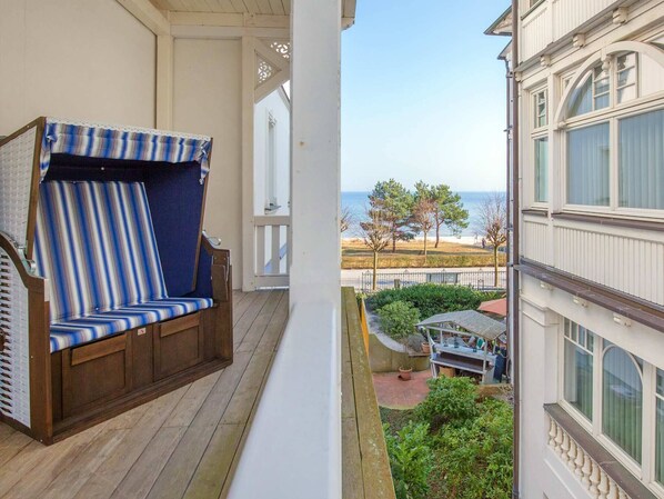 A balcony with a striped chair and a view of the beach.