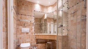 Une salle de bain moderne avec une douche à parois de verre, des toilettes blanches et un meuble-lavabo avec un miroir.