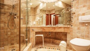 Une salle de bain avec une douche à parois de verre, un meuble-lavabo avec un miroir et des toilettes.
