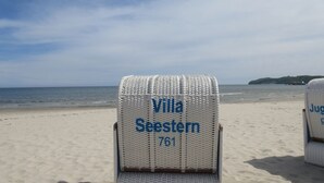 A beach chair labeled "Villa Seestern 761" on a sandy beach with the ocean in the background. - Apartment with sea view, 2 bedrooms and balcony (Ostseebad Binz)
