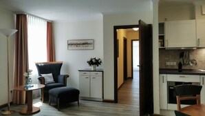 A modern hotel room with a dining area, a kitchenette, and a view of the hallway. - Apartment with sea view, 2 bedrooms and balcony (Ostseebad Binz)