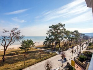 A coastal view with a beach, trees, and a pathway.