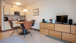 Eine moderne Küche mit Essbereich, darunter ein runder Tisch mit Stühlen, eine Mikrowelle und ein Fernseher auf einer Holzkommode.