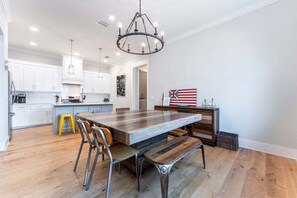 A modern kitchen with a large island, white cabinets, and a chandelier. - Luxury St. Simons Island Vacation Rental with Private Saltwater Pool | Royal Fortune (St. Simons Island)