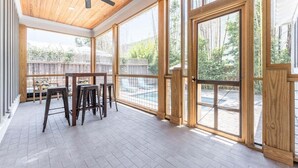 A spacious room with a wooden ceiling, large windows, and a view of a backyard.