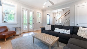 A spacious living room with a dark-colored sofa, a wooden coffee table, and a ceiling fan.